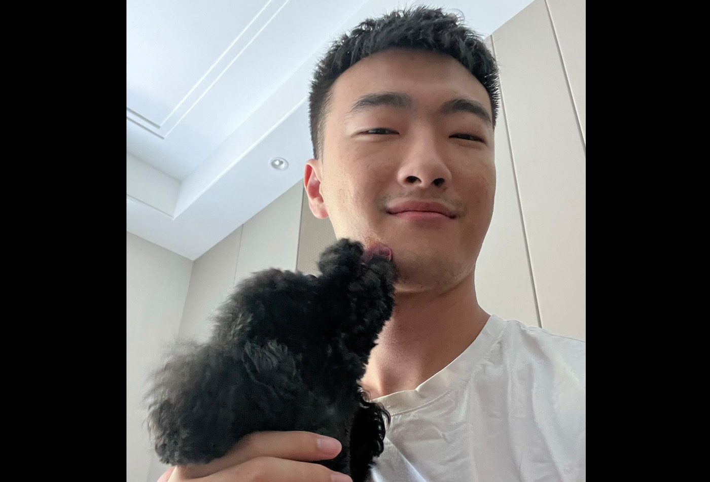 Chonghe Zhang smiles with a black poodle.